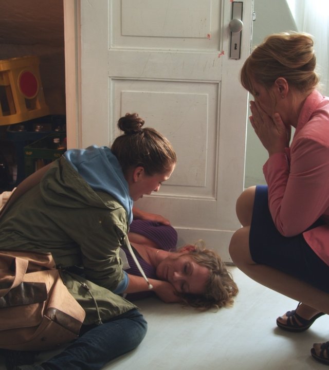 "SOKO Wismar - Kammerflimmern": Daniela Carstensen liegt regungslos auf dem Boden. Ilka Carstensen (Henriette Confurius) ist kniend über sie gebeugt und Bettina Rauch (Nina Vorbrodt) sitzt in der Hocke vor ihr.