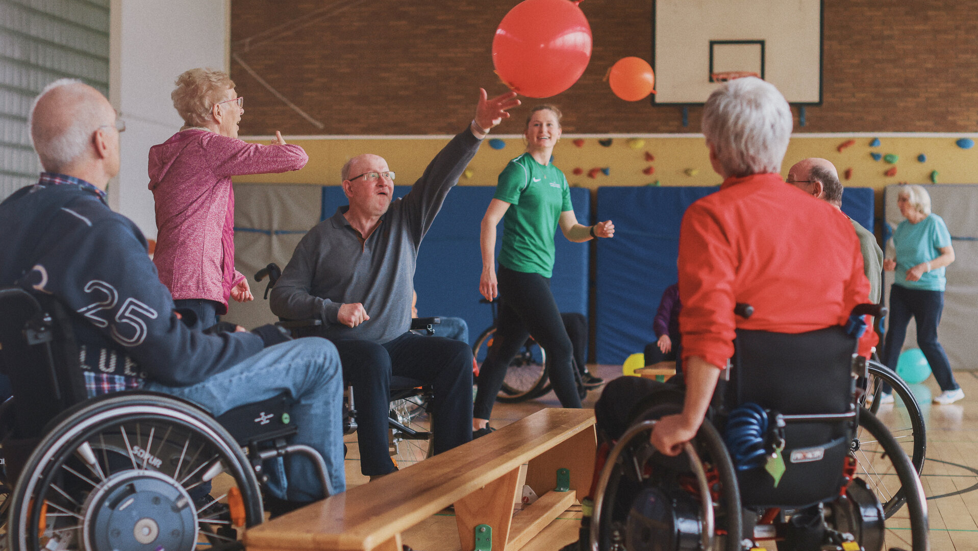 "Aktion Mensch - Glückszahlen der Woche": in einer Sporthalle sind mehrere Menschen versammelt und spielen mit einem roten Ball. Einige sitzen in Rollstühlen.