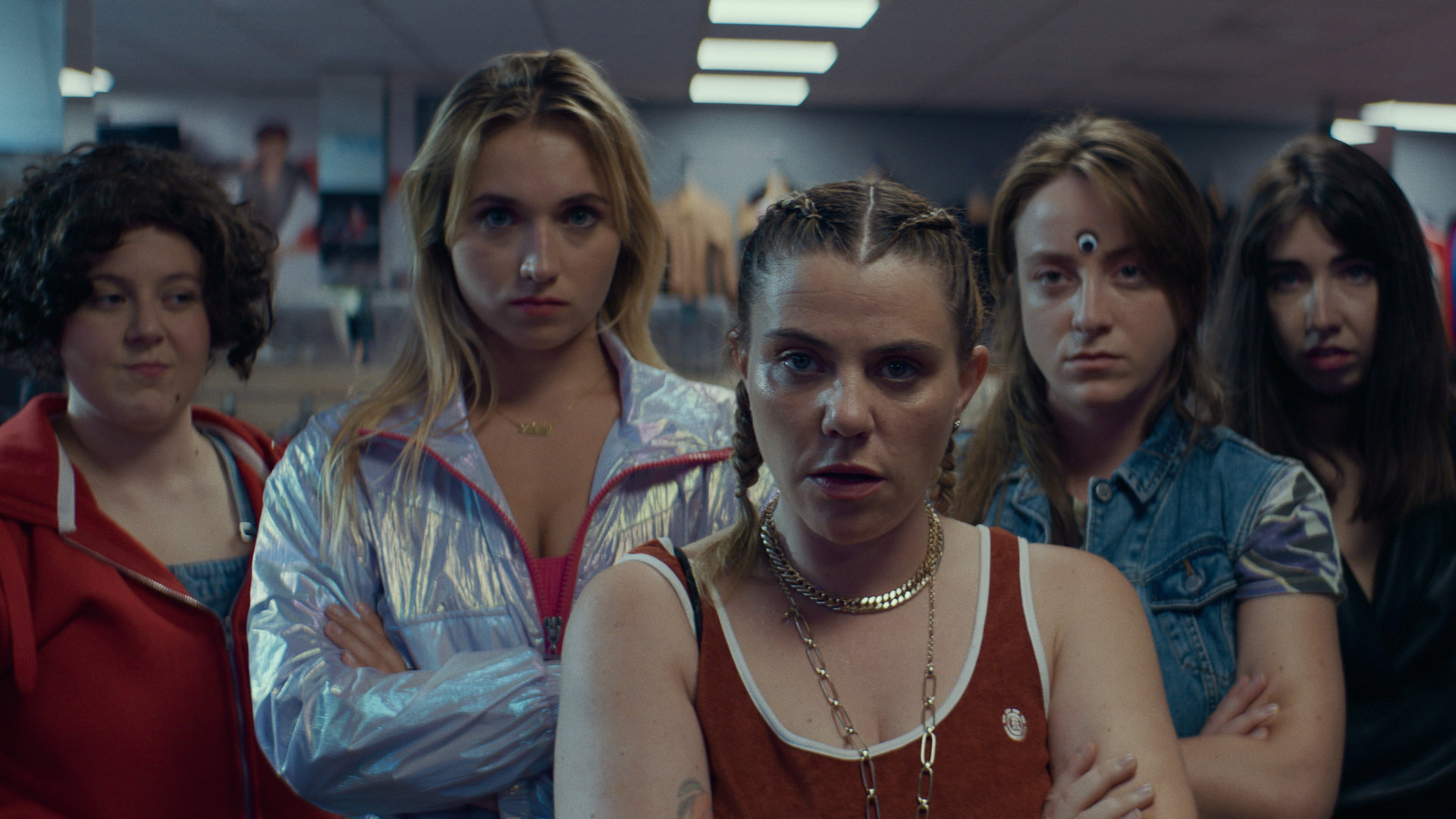 "Derby Girl - Stich ins Wespennest": MJ (Salomé Diénis Meulien), Lola (Chloé Jouannet), Mother Blocker (Sophie-Marie Larrouy), Booby Mercury (Allison Chassagne) und Absinthe (Suzanne De Baecque) stehen nebeneinander in einem Laden und schauen ernst nach vorne.