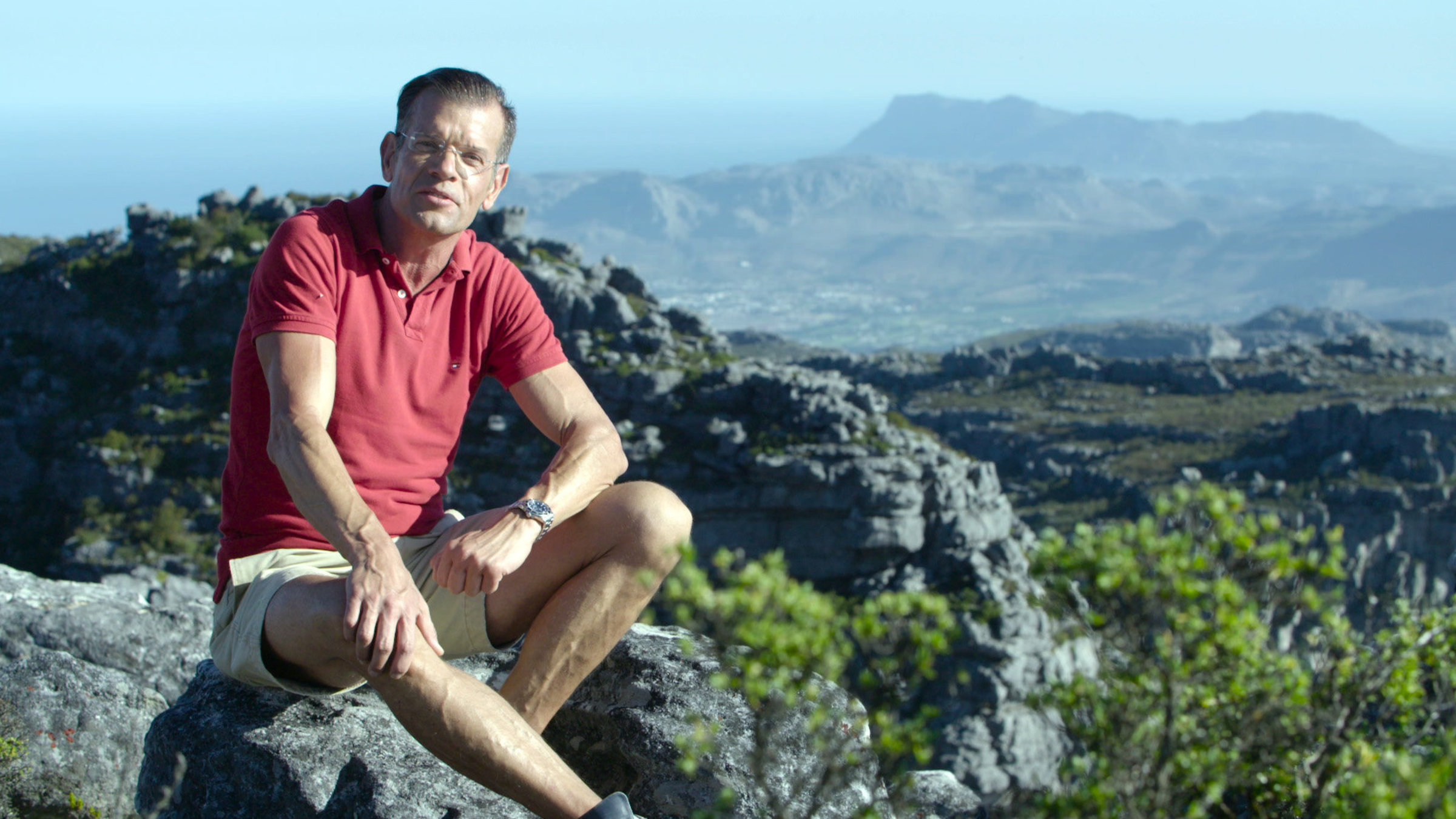"Traumgärten am Kap - Mit dem Biogärtner in Südafrika": Karl Ploberger sitzt auf einem Felsen. Im Hintergrund das Kap.