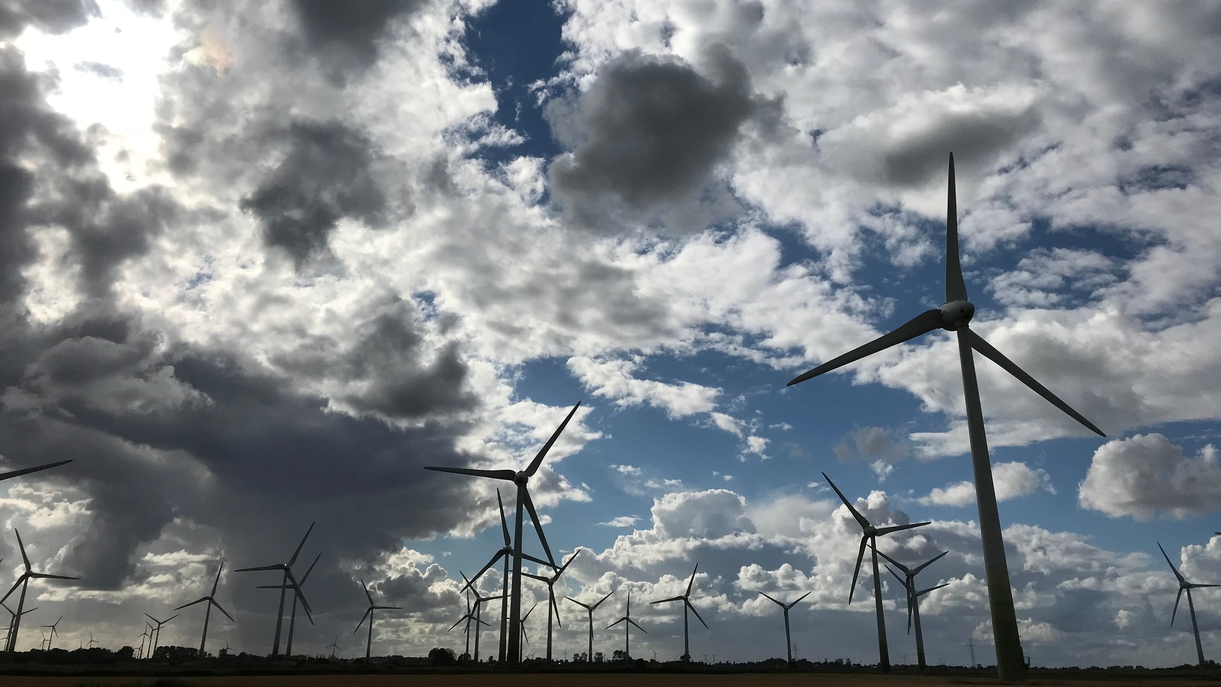 "planet e.: Infraschall - Unerhörter Lärm": Ein Windrad-Feld vor leicht bewölktem Himmel.