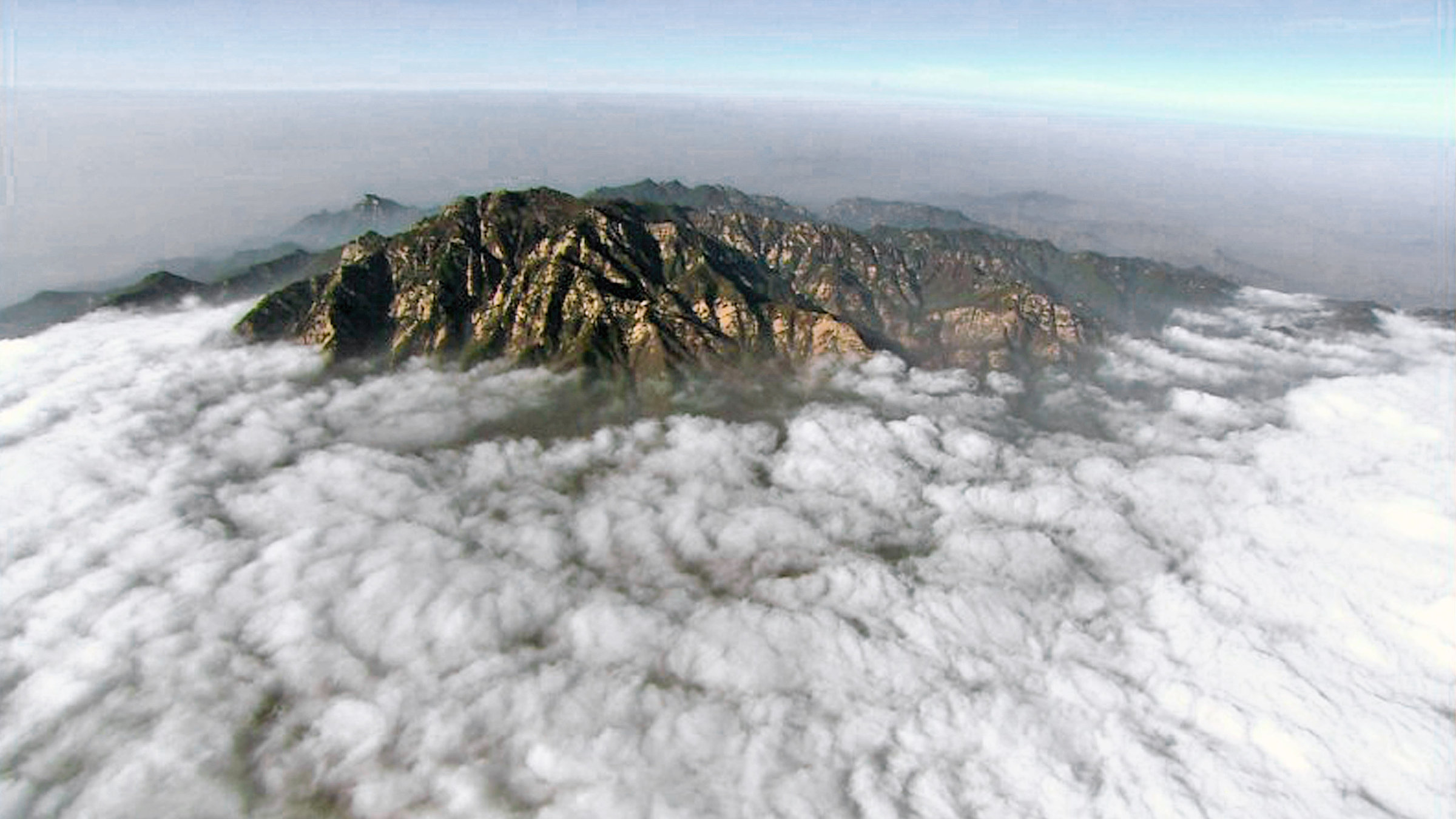 "Chinas mythische Berge (3/3) - Tai Shan": Blick auf den Berg Tai Shan, der teilweise von Wolken umhüllt ist.