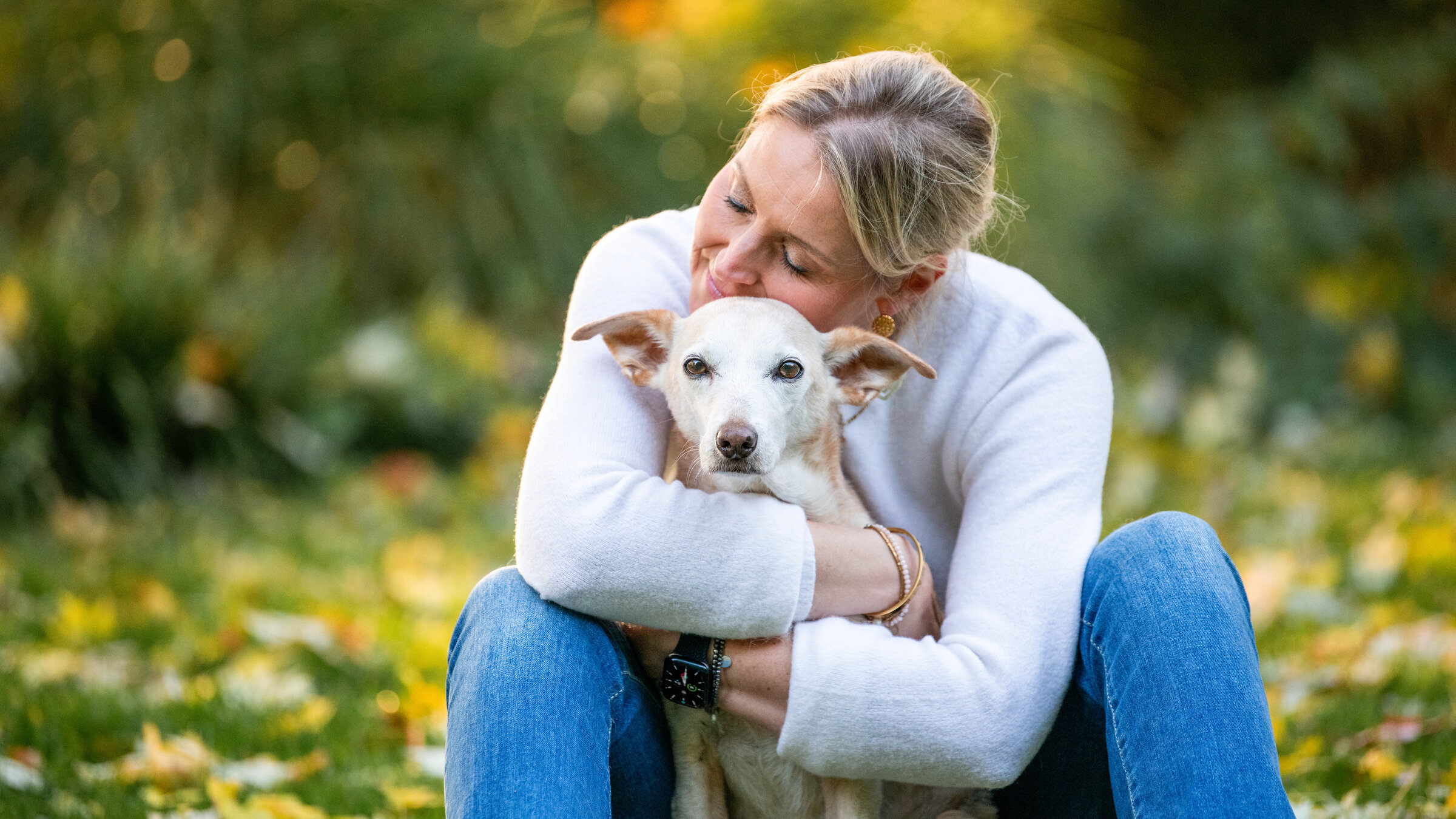 "37°: Wenn Haustiere alt werden - Moppis letzter Sommer": Carmen sitzt hinter Hündin Mila auf einer Wiese und umarmt sie liebevoll.