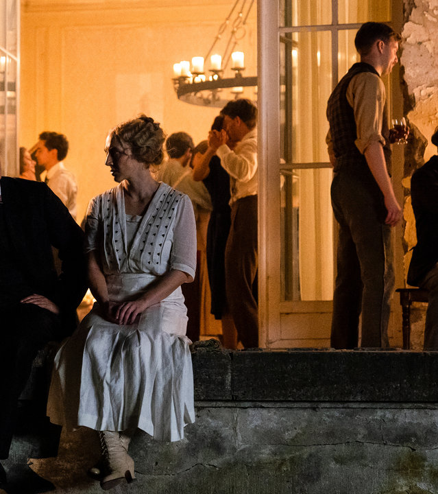 "Die Neue Zeit - 1. Nach dem Krieg": Walter Gropius (August Diehl) und Dörte Helm (Anna Maria Mühe) sitzen auf der Mauerumrandung einer Veranda und unterhalten sich. Im Hintergrund findet eine Party mit zahlreichen Kommilitonen statt. Kerzen verbreiten eine angenehme Atmosphäre.