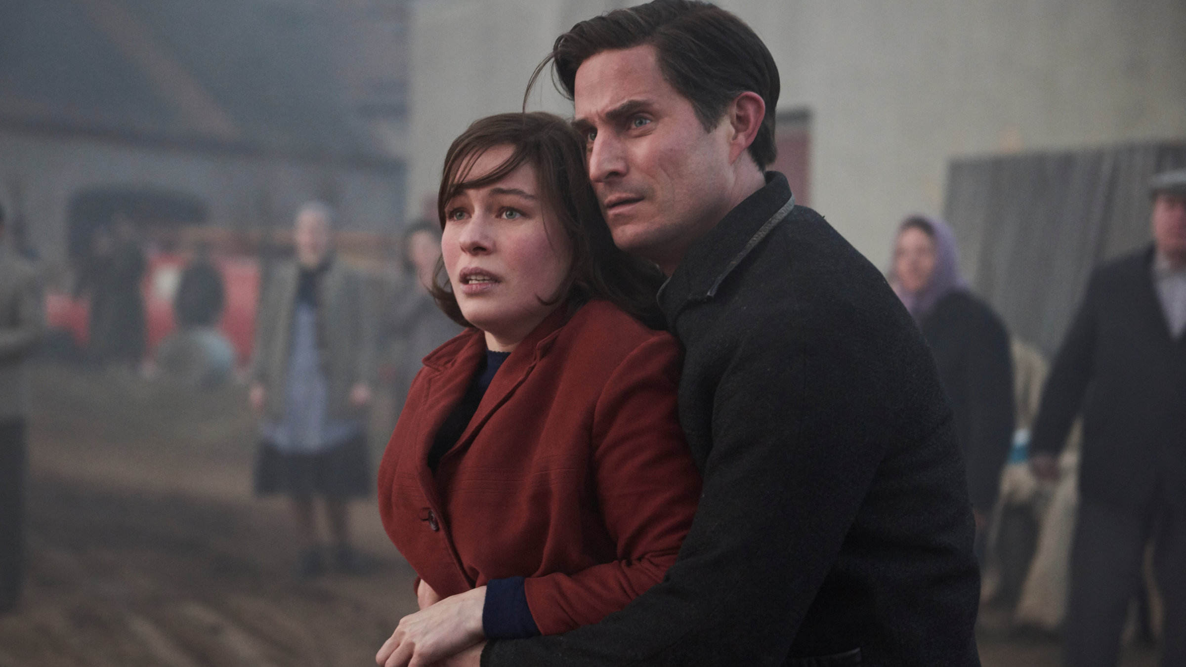 "TANNBACH - Schicksal eines Dorfes : Schatten des Krieges": Pastor Wolfgang Herder (Clemens Schick) hat seine Arme um Annas (Henriette Confurius) Taille gelegt und drückt sie fest an sich. Sie schauen in die gleiche Richtung.