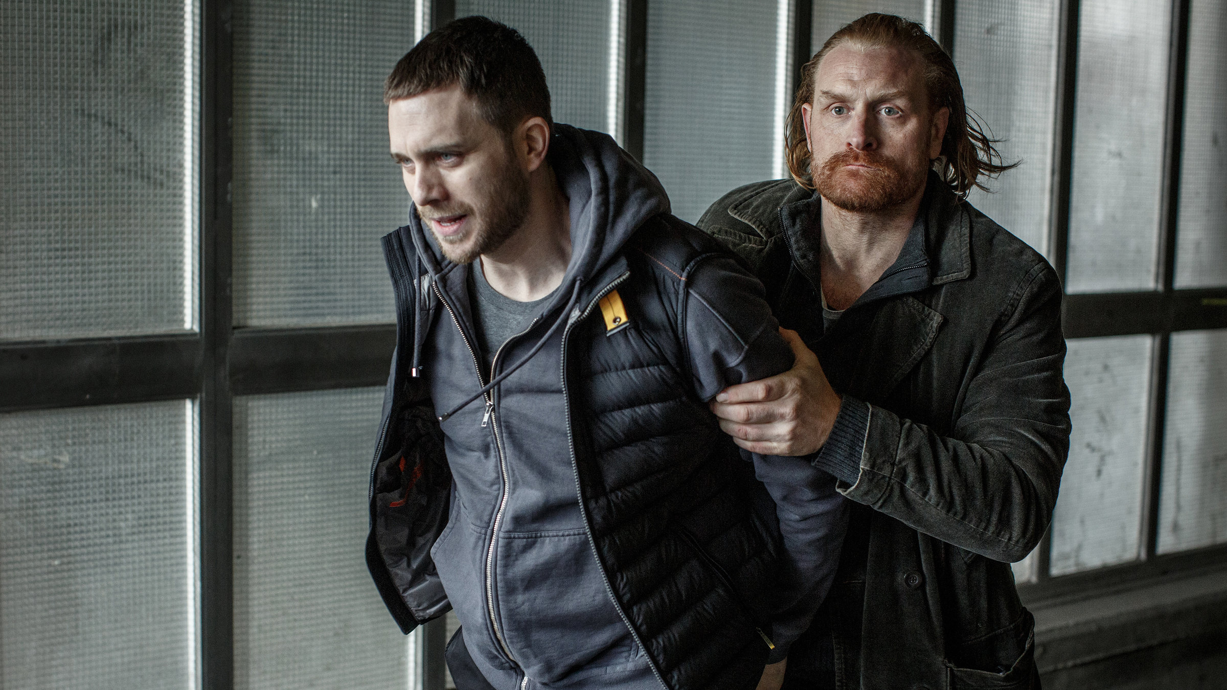 "Kommissar Beck: Undercover": Mit seinen Händen hinter dem Rücken wird Josef Eriksson (Martin Wallström) von einem entschlossen dreinblickenden Steinar Hovland (Kristofer Hivju) abgeführt.