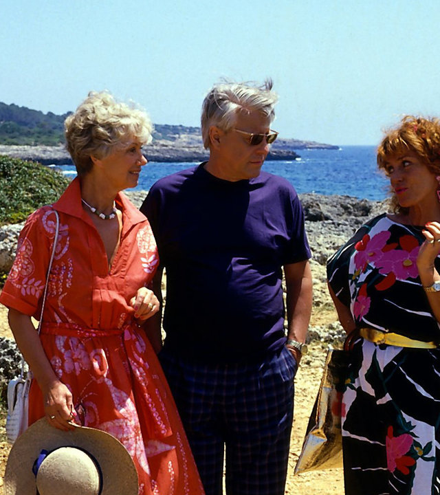 "Die Wicherts von nebenan: Spanische Zeiten": Hannelore (Maria Sebaldt) und Eberhard (Stephan Orlac) stehen neben Frau Lallinger (Gabi Gasser) und blicken sie fragend an. Im Hintergrund ist das Meer zu sehen.