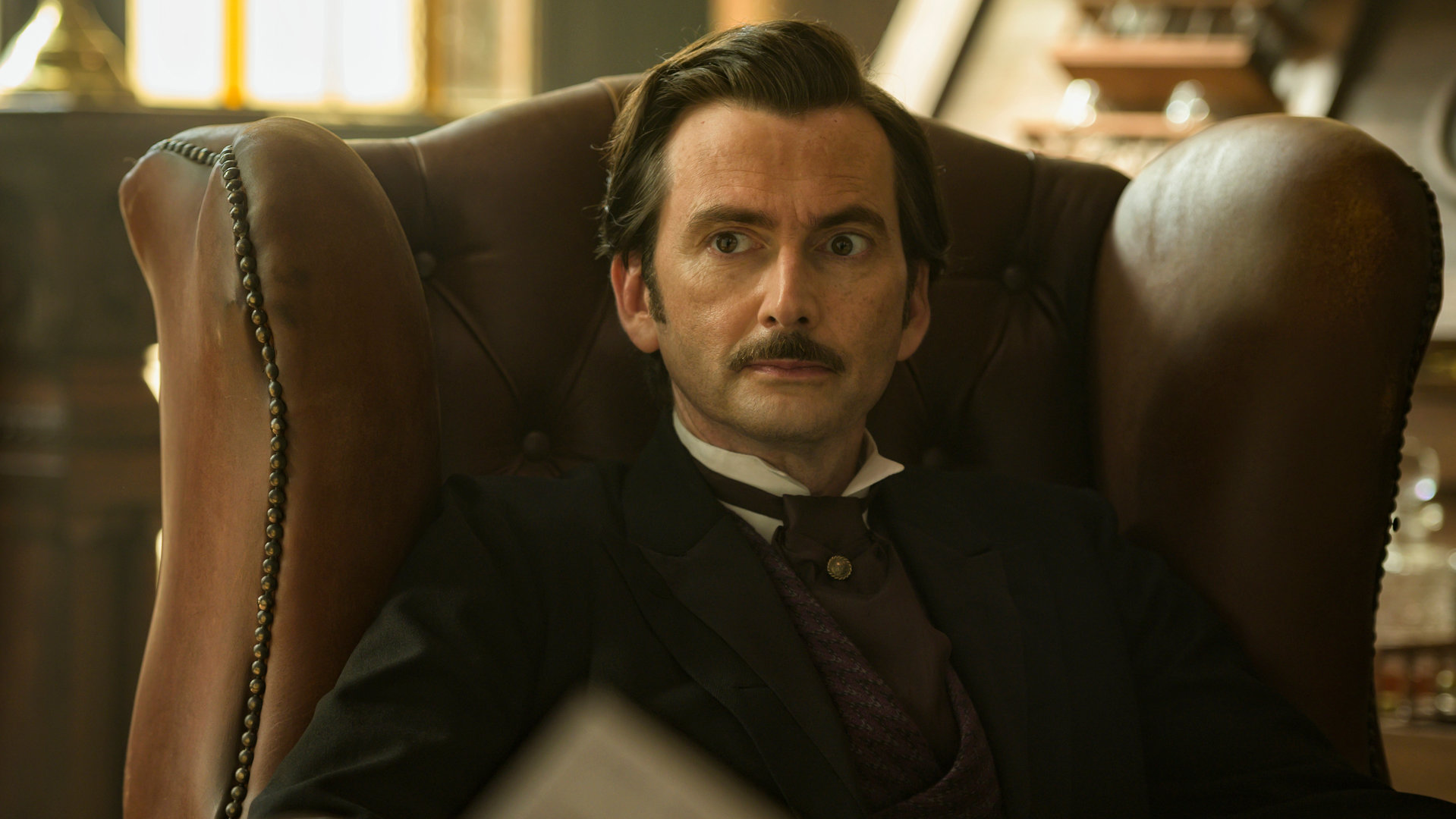 "In 80 Tagen um die Welt (1)": Akkurat frisiert und gekleidet sitzt Phileas Fogg (David Tennant) in einem braunen Ledersessel und blickt versonnen in den Raum.