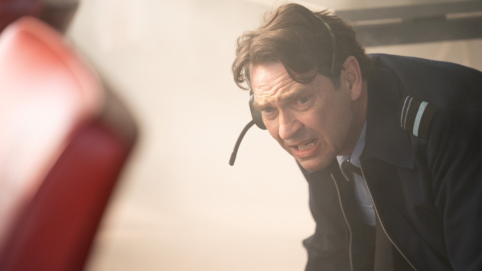 "Vigil - Tödliche Drohnen: Attacke": Air Marshal Marcus Grainger (Dougray Scott) duckt sich panisch und erschrocken nach unten weg. Er trägt ein Head-Set.