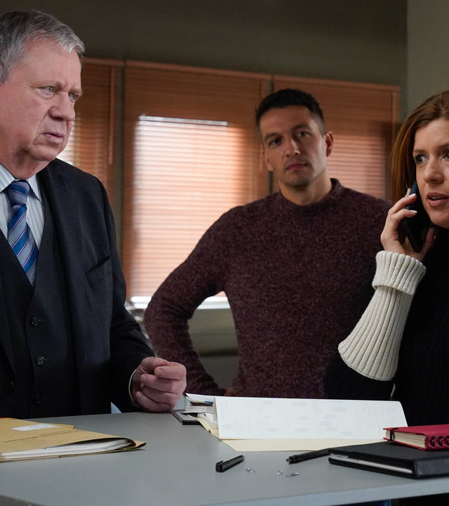 "Der Staatsanwalt - Tödliches Erbe": Oberstaatsanwalt Bernd Reuther (Rainer Hunold) steht mit Hauptkommissarin Kerstin Klar (Fiona Coors) an einem Besprechungstisch. Kerstin Klar telefoniert, während Oberkommissar Max Fischer (Max Hemmersdorfer) aus dem Hintergrund zusieht.