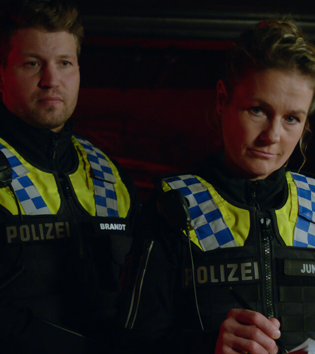 "Notruf Hafenkante - Letzter Einsatz": Der Polizist Nick Brandt (Raúl Richter) und seine Kollegin Franzi Jung (Rhea Harder-Vennewald) stehen nebeneinander in einem Club. Franzi hält ein Notizbuch und einen Stift in den Händen und blickt ernst auf etwas vor sich.