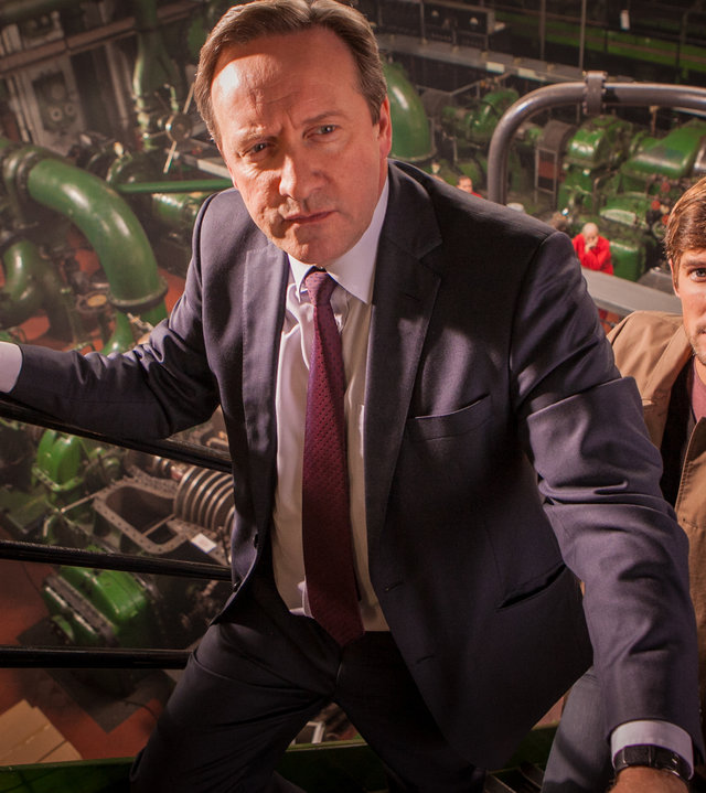 "Inspector Barnaby - Barnaby muss reisen": Barnaby (Neil Dudgeon) und Nelson (Gwilym Lee) steigen über eine Treppe aus der Produktionshalle der Keksfabrik hinauf.