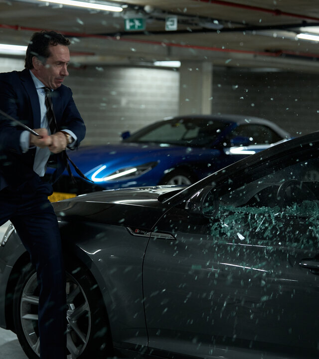 "Elixir – The Pain Killers - Das Versprechen": In einem Parkhaus schlägt Juliën (Jacob Derwig) mit einem Golfschläger auf ein dort abgestelltes Auto ein. Die Scheibe des Fensters auf der Fahrerseite zerspilttert gerade.