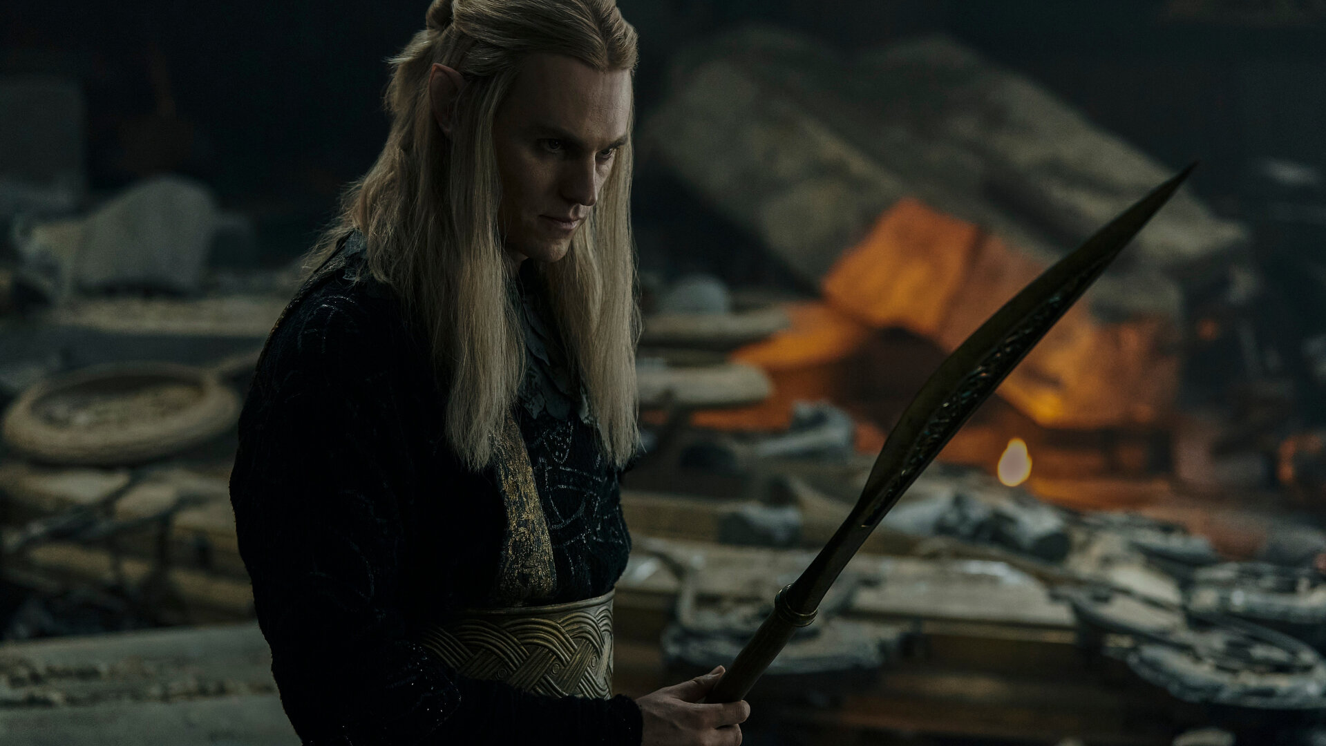 "Der Herr der Ringe: Die Ringe der Macht - Schatten und Flammen": Sauron (Charlie Vickers) steht in einem Raum, in dem Gegenstände verstreut herumliegen. Er hält ein Schwert in der Hand.