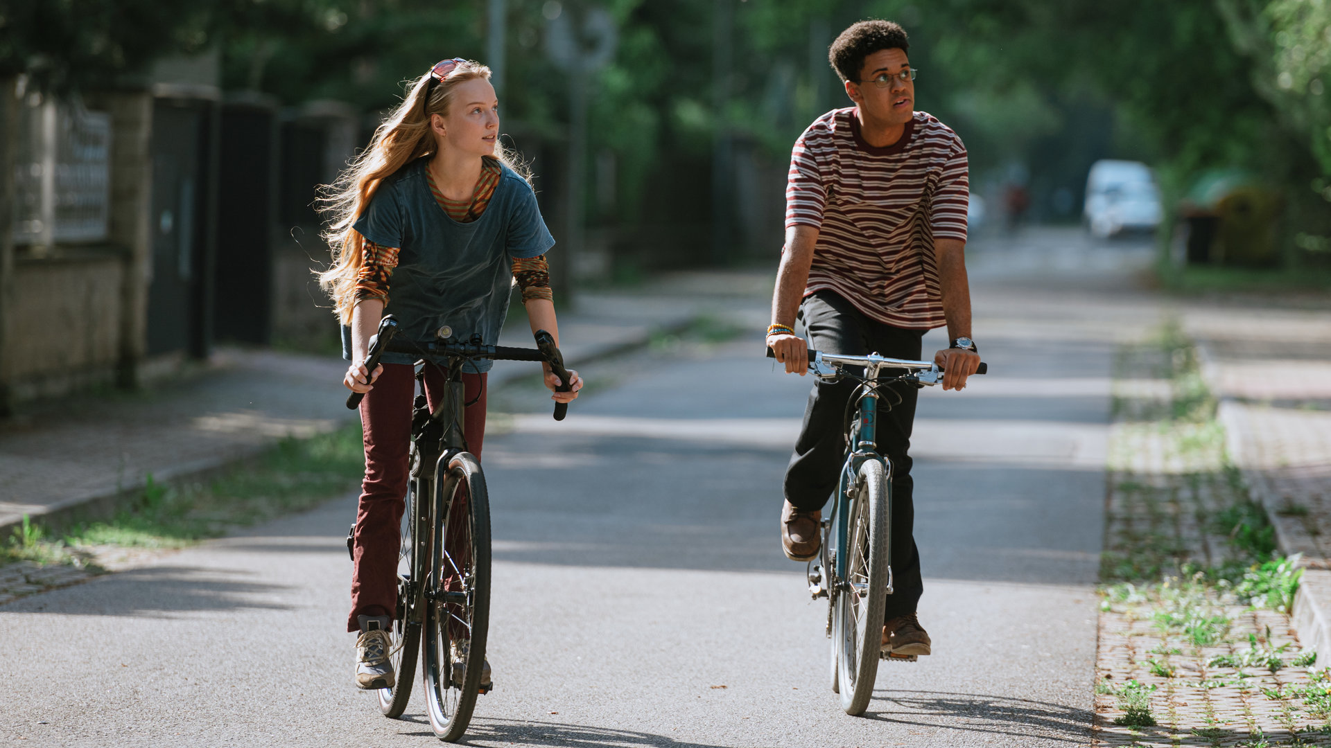 "Was wir fürchten - Gefangen":  Lisa Abel (Mina-Giselle Rüffer, l.) fährt mit ihrem Fahrrad auf einer Straße. Neben ihr fährt ihr Mitschüler Davi Cruz (Esmael Agostinho, r.).