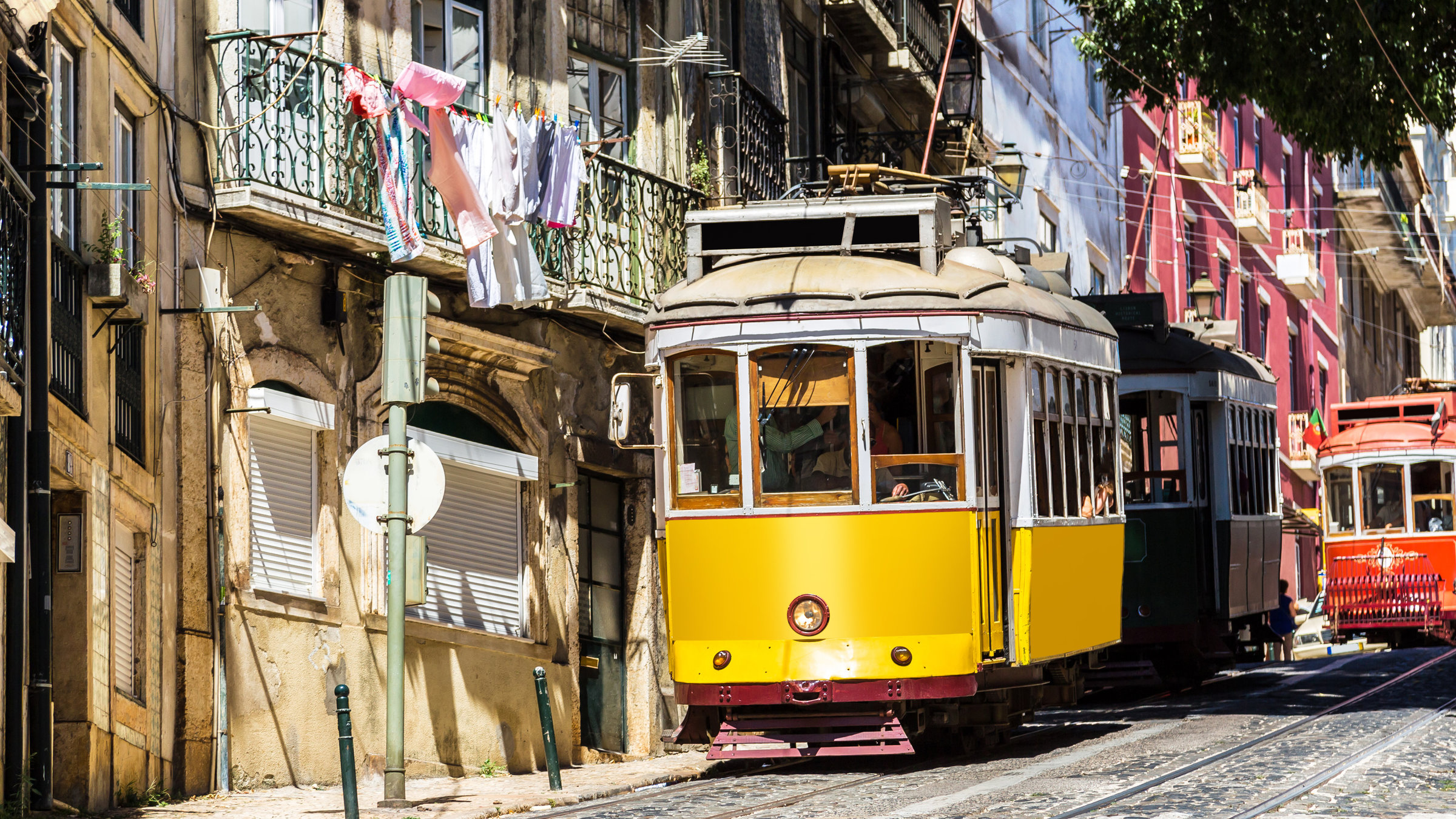 Portugal lesen!: Eine typische altmodische Straßenbahn fährt eine enge Gasse in der Lissaboner Altstadt hinab
