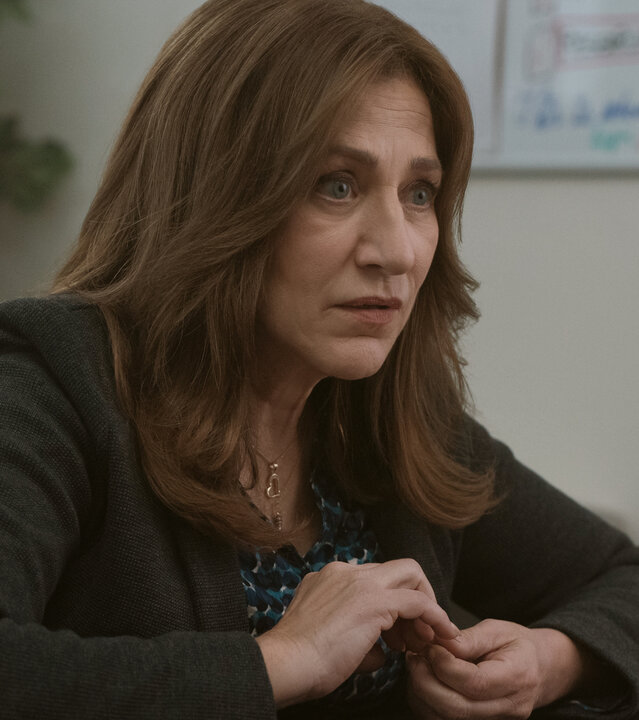 "Bupkis - Crispytown": Amy Davidson (Edie Falco) sitzt, mit grünem Jackett und an den Nägeln kribbelnd, am Laptop. Sie wirkt schockiert.