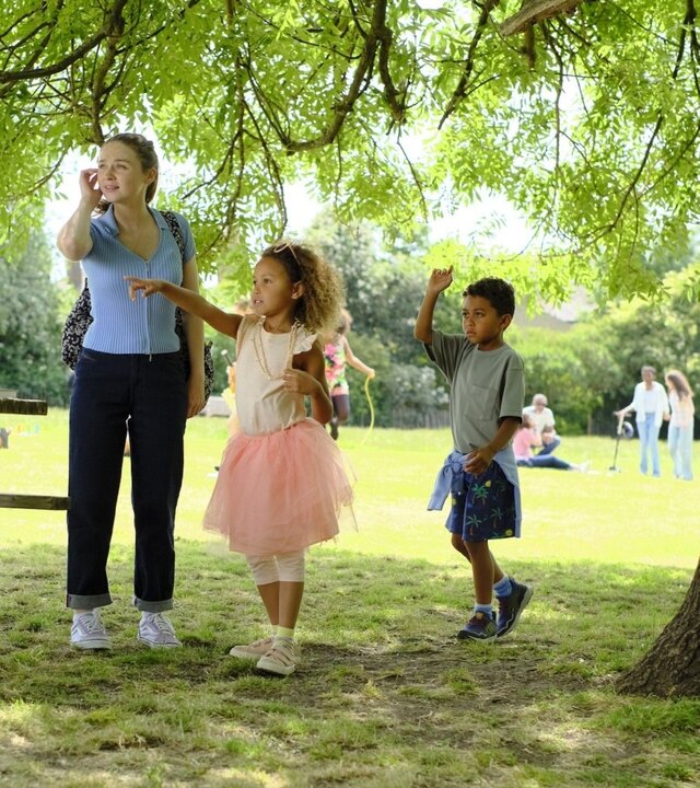 "You & Me": Emma (Jessica Barden) steht im Park und schaut sich verwirrt um, während die Kinder Poppy (Isabella Tyson) und Jack (Lucas Tyson) neben ihr stehen und entschlossen in eine Richtung zeigen.