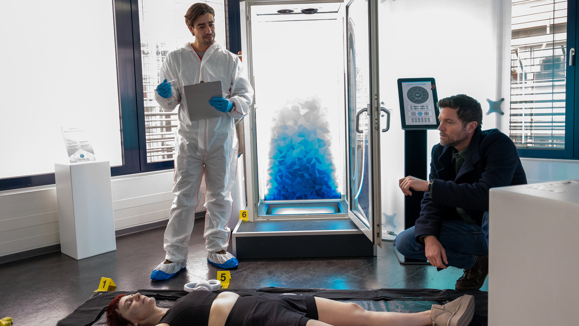"SOKO Stuttgart - Kalter Tod": In einem Studio für Kältetherapie steht Rechtsmediziner Dr. Benedikt Förster (Florian Wünsche) vor einer Kältekammer und erörtert mit Jo Stoll (Peter Ketnath) seine ersten Erkenntnisse. Der Kriminalkommissar kniet vor der Frauenleiche, der Geschäftsführerin des Studios Barbara Döring (Yvy Heußler).