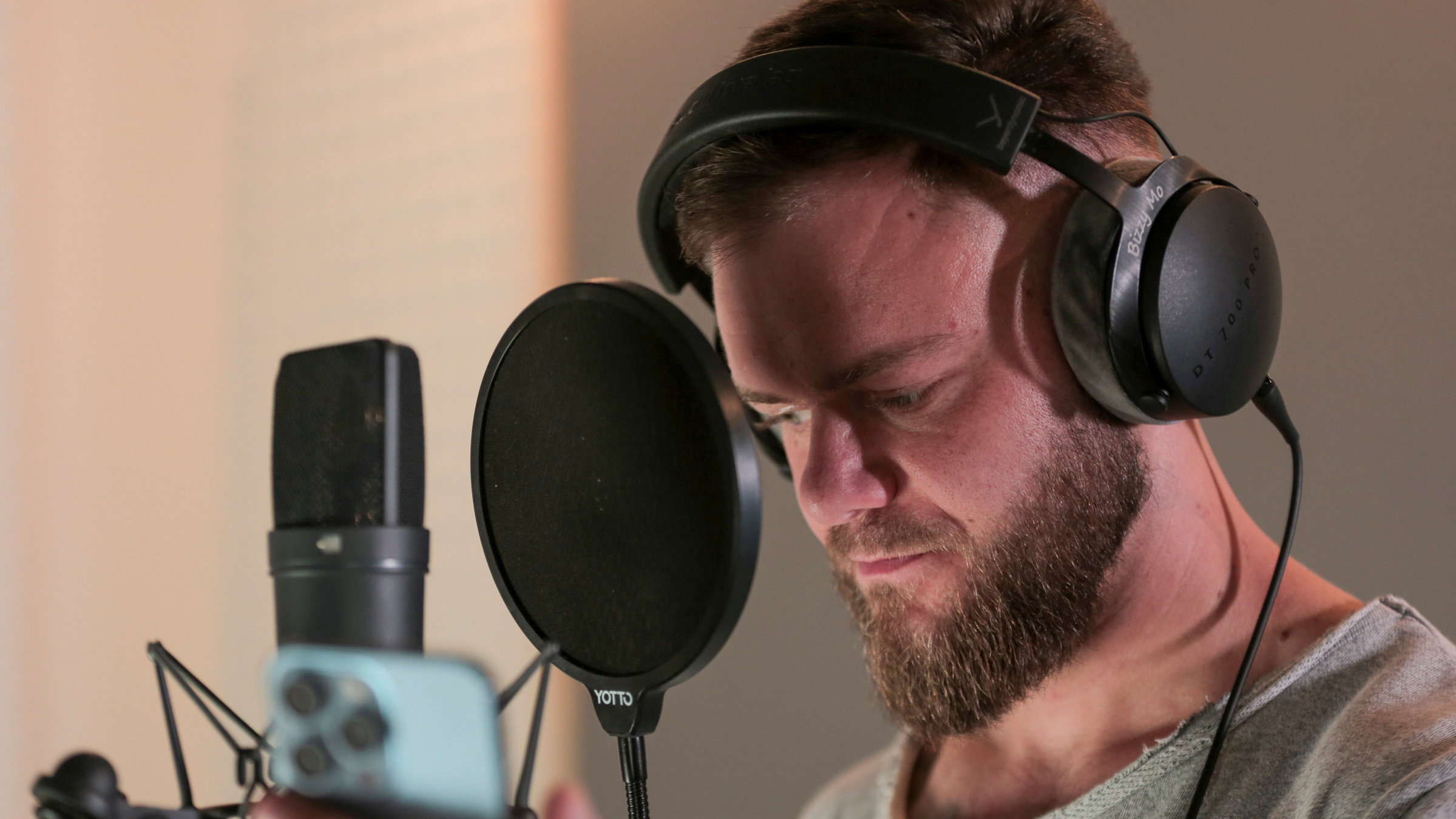"37° Jedes Wort ein Sieg - Mein Stottern hält mich nicht auf": Artjom in der Tonkabine. Er trägt Kopfhörer und steht vor einem Mikrofon.