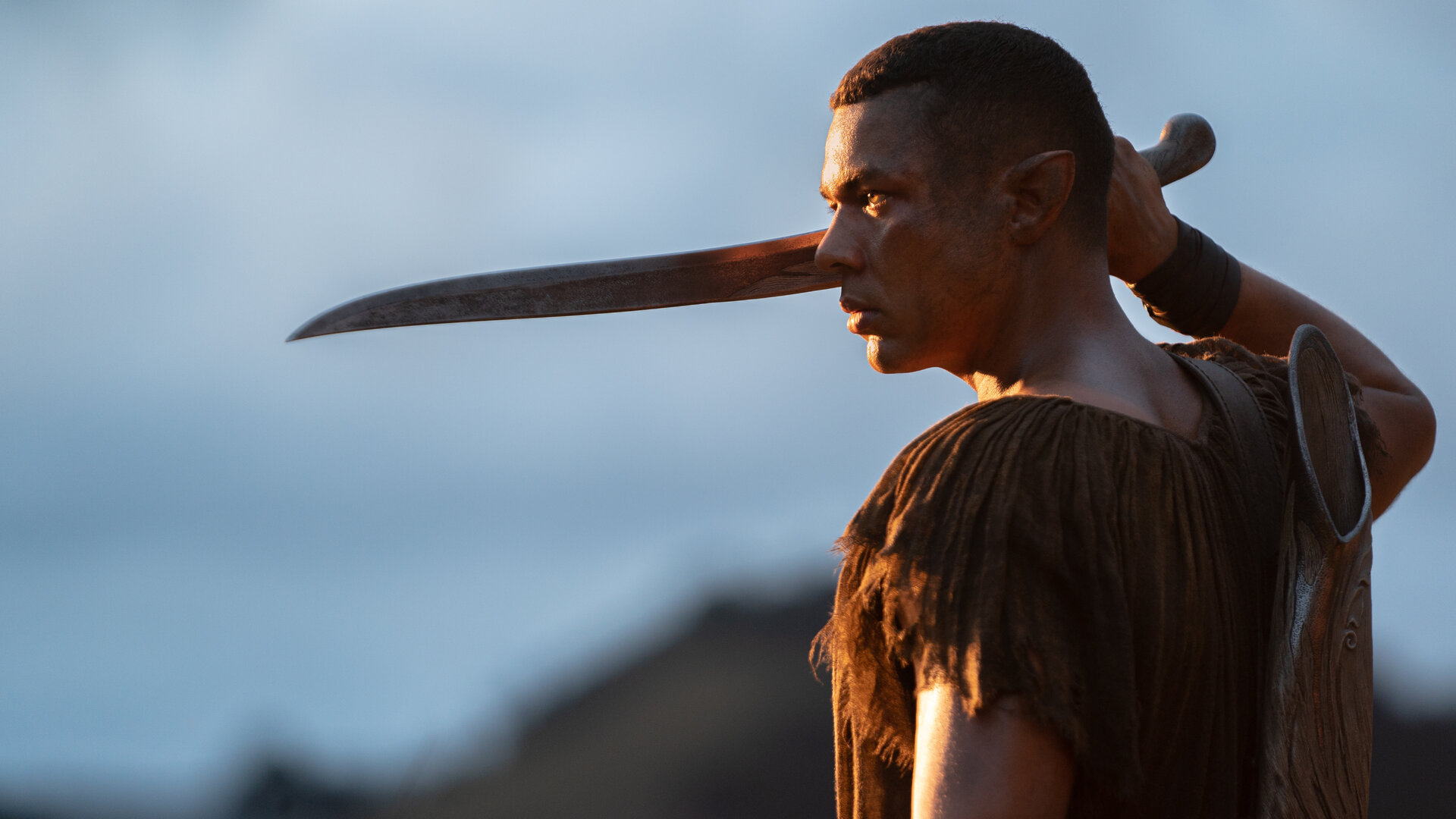 "Der Herr der Ringe: Die Ringe der Macht - Die Große Woge": Arondir (Ismael Cruz Córdova) steht im Freien. Er hält einen langen Dolch in der rechten Hand.