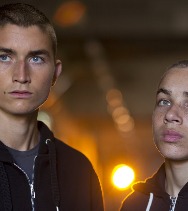 "Springflut - Vergeltung": Liam (Gustav Lindh) und Adam (Dakota Trancher Williams) stehen in dunklen Sweatshirt-Jacken mit Kapuzen in einem Keller, und ihr ernster Blick schweift in die Ferne.