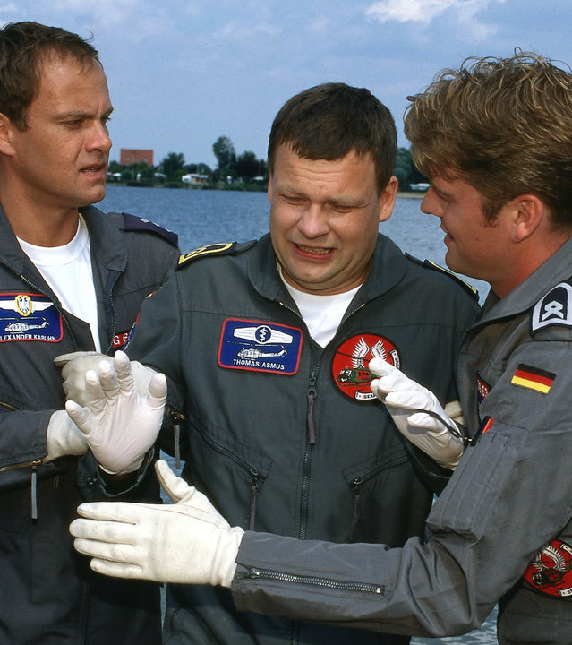 "Die Rettungsflieger - Abschied von Thomas": Alex (Matthias Leja) und Wollcke (Oliver Hörner) stehen rechts und links von dem verzweifelt schauenden Thomas (Ulrich Bähnk). Hinter ihnen der See.
