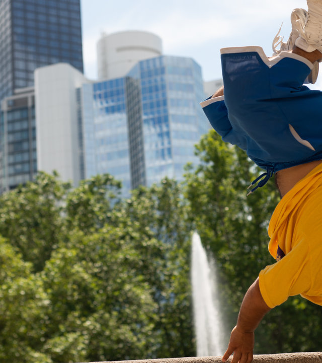 "Einfach Mensch - Mach Dein Ding": Ihab Yassin macht einen Handstand auf einer Mauer. Im Hintergrund eine Skyline.