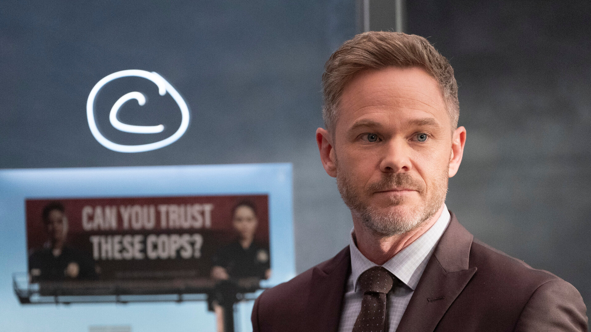 "The Rookie - Drei Billboards": Wesley Evers (Shawn Ashmore) steht vor einer Tafel, auf der ein großer Buchstabe, sowie verschiedene Stadteile verzeichnet sind. Außerdem ist ein Foto von einer großen Werbetafel darauf angebracht. Wesley blickt interessiert nach vorn.