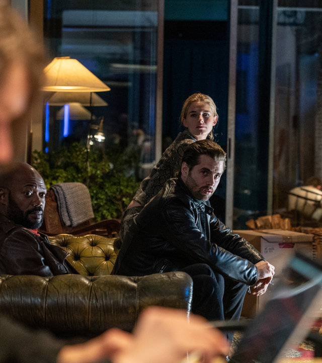 "The Bank Hacker": Jeremy (Tijmen Govaerts) sitzt vor einem Laptop, während Souleymane (Claude Musungayi), Ada (Ella-June Henrard) und Prince (Manuel Broekman) zu ihm blicken und ihn beobachten.