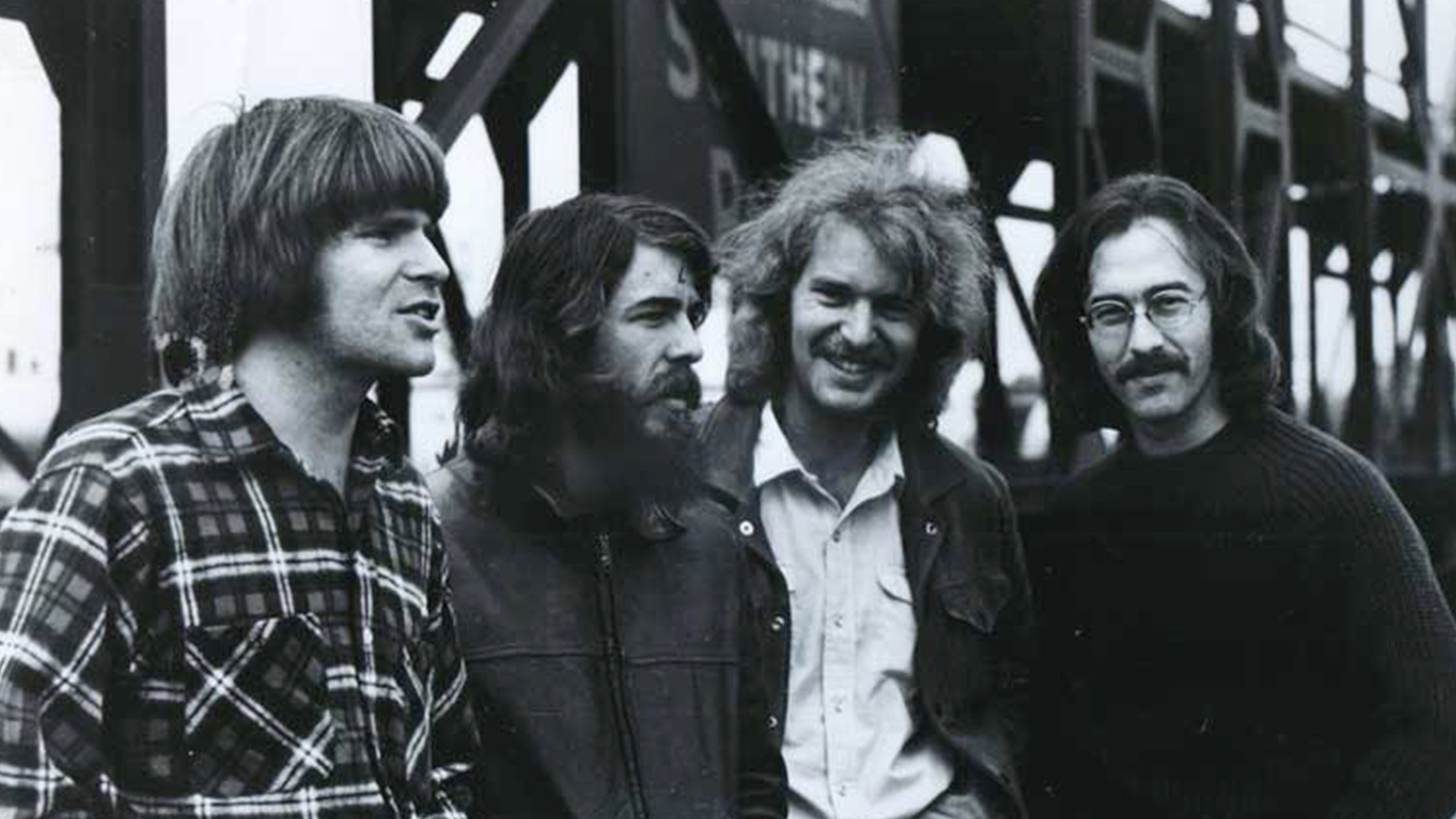 "Creedence Clearwater Revival: Live at The Royal Albert Hall":  s/w-Foto der Band Creedence Clearwater Revival. Die Mitglieder der Band stehen nebeneinander. Im Hintergrund eine Eisenbahnbrücke.