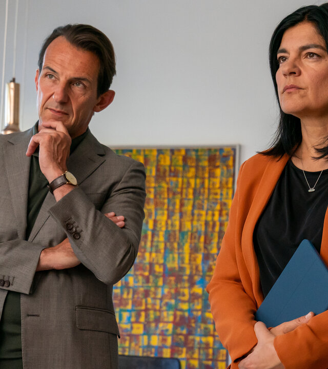 "Letzte Spur Berlin - Luftschlösser": Oliver Radek (Hans-Werner Meyer) und Mina Amiri (Jasmin Tabatabai) stehen nebeneinander im Raum. Ihre Blicke sind ernst nach vorne gerichtet.
