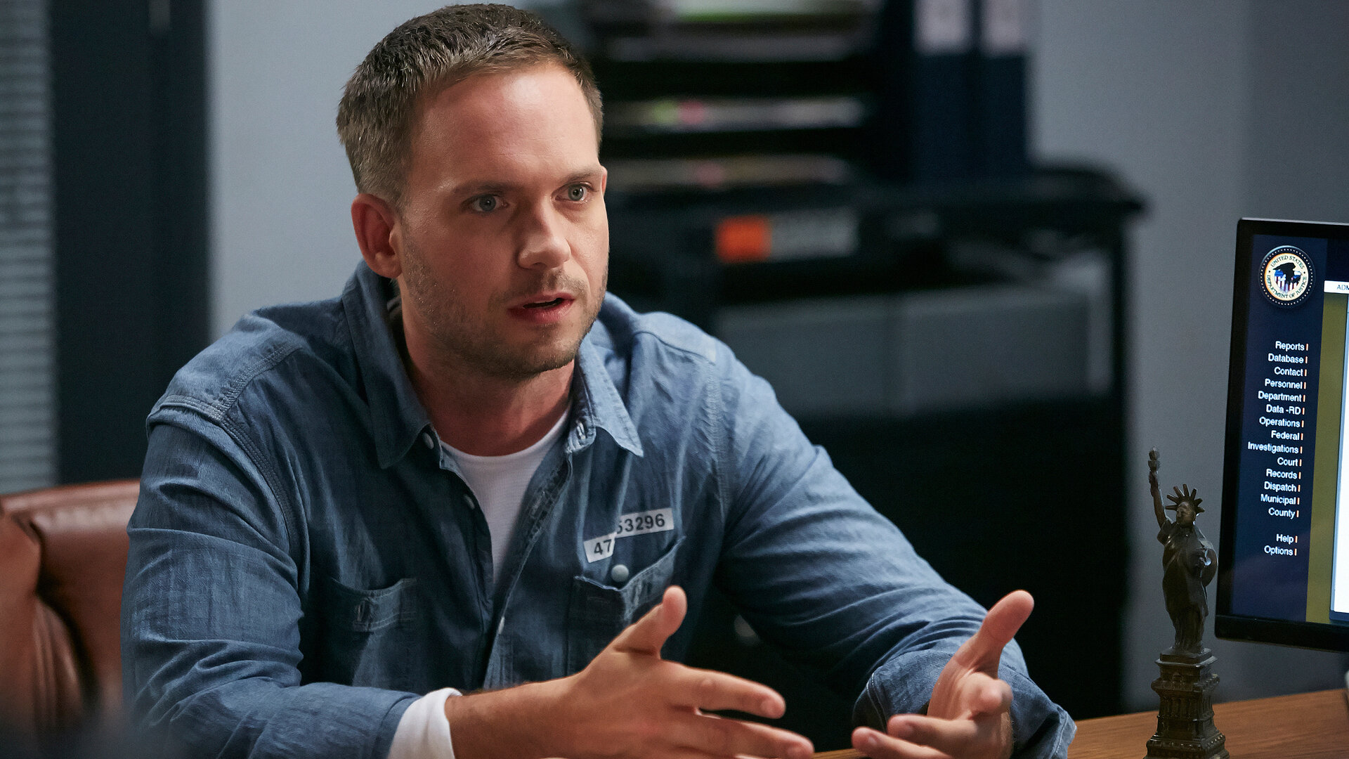 "Suits - Vertrauen": Mike (Patrick J. Adams) sitzt an einem Tisch während er spricht und gestikuliert. Er schaut ernst nach vorne.