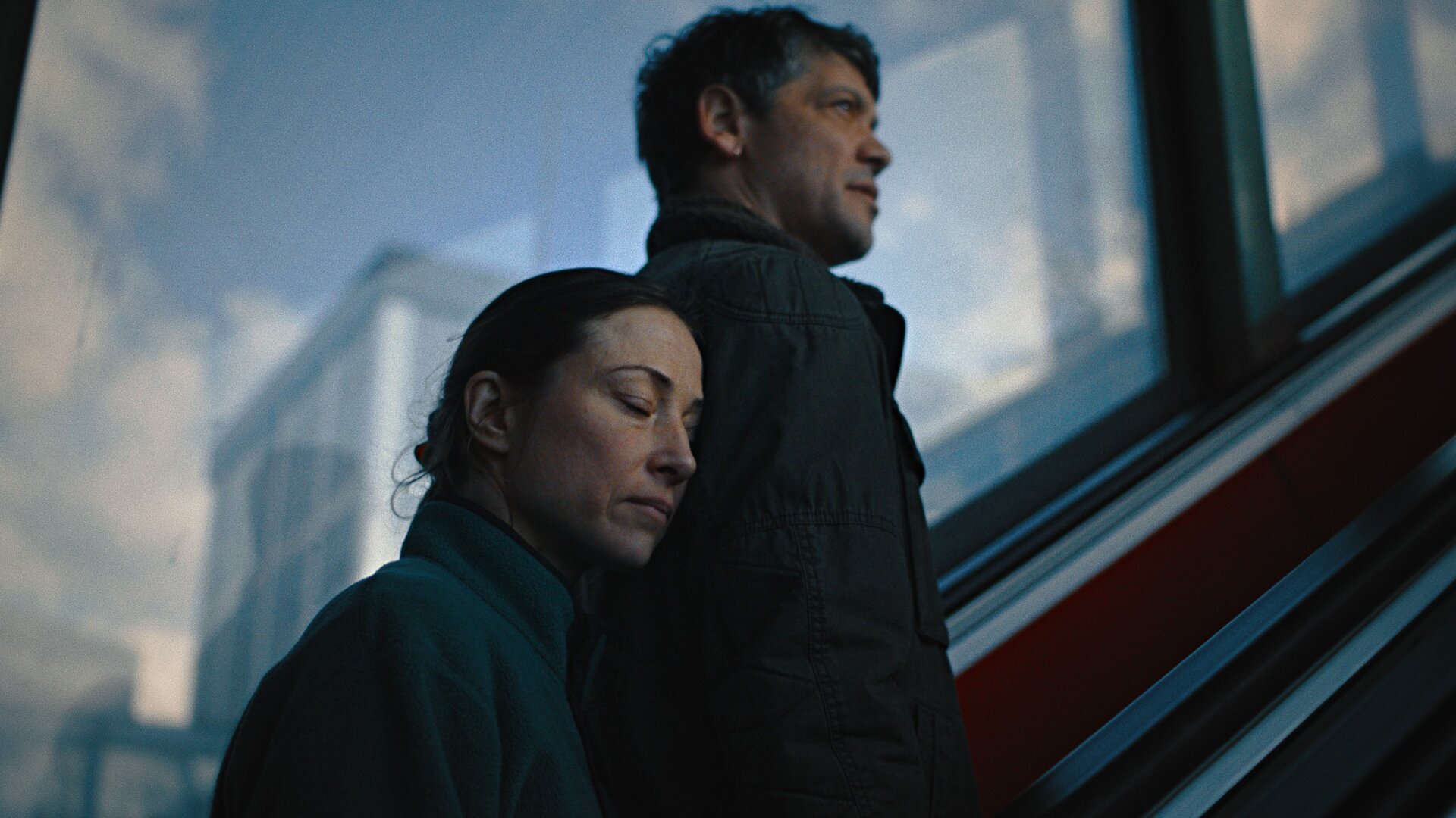 "Alle die Du bist": Nadine (Aenne Schwarz) legt mit geschlossenen Augen ihren Kopf an Pauls (Carlo Ljubek) Schulter, während sie eine Rolltreppe hochfahren.