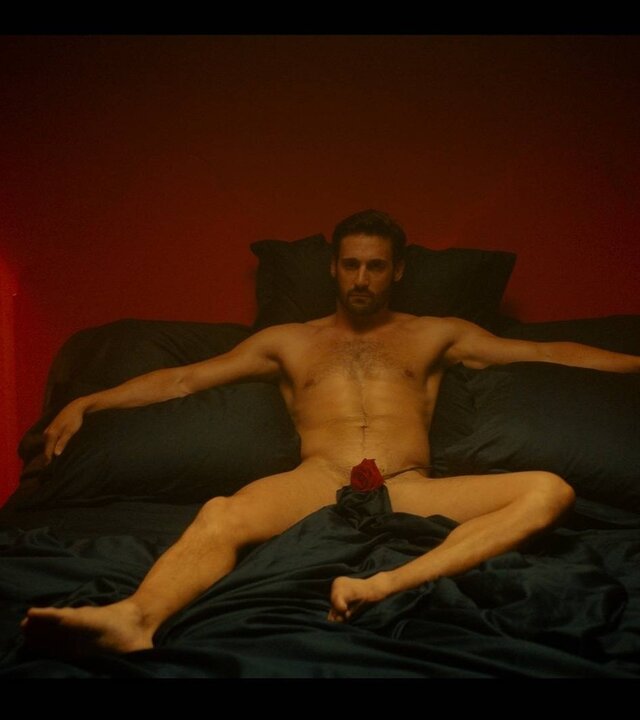 "Escort Boys - Ein letztes Mal": Ben (Guillaume Labbé) liegt nackt auf einem schwarzen Bett in einem Schlafzimmer. Eine Rose bedeckt seinen Schoß. Das Licht ist gedimmt, auf dem Nachttisch brennen Kerzen und tauchen den Raum in warmes Licht.