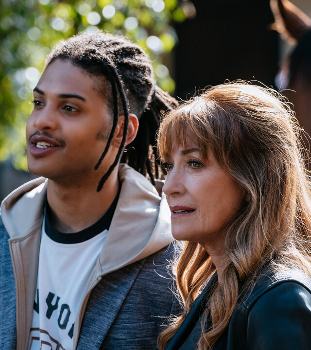 "Harry Wild – Mörderjagd in Dublin - Die Geschichte vom toten Pferd": Fergus Reid (Rohan Nedd) und Harry Wild (Jane Seymour) stehen nebeneinander im Freien. Hinter ihnen ist in der Unschärfe ein Pferd zu erkennen.