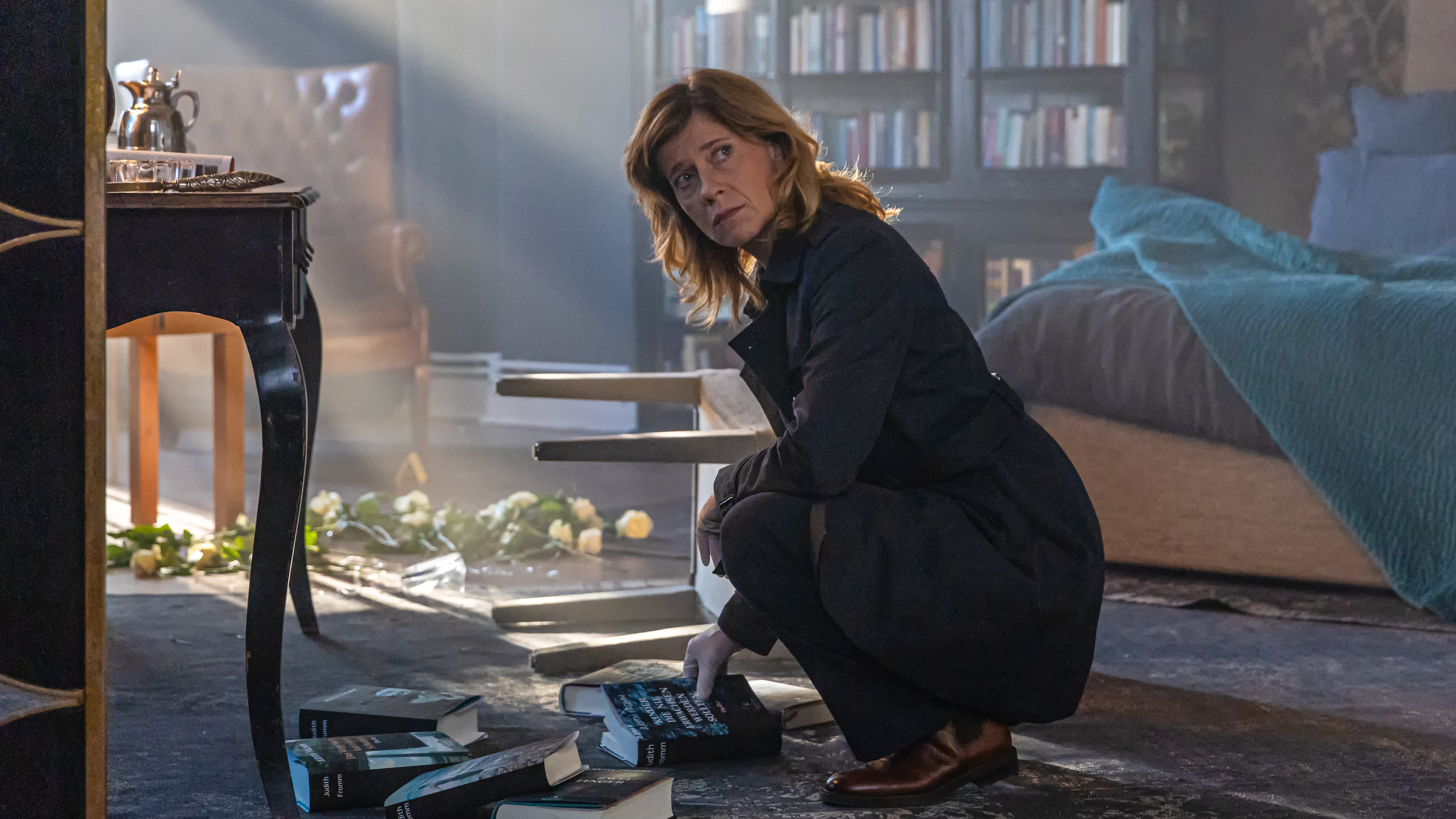 "Kolleginnen - Für immer": Irene Gaup (Caroline Peters) hockt in einem dunklen Wohnzimmer. Vor ihr liegen Bücher verstreut.