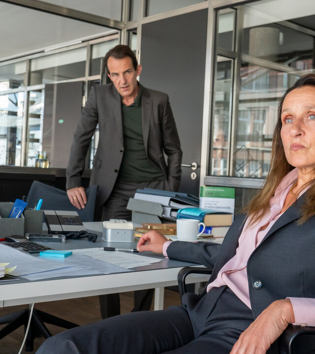 "Letzte Spur Berlin - Danach": Mina Amiri (Jasmin Tabatabai) und Oliver Radek (Hans-Werner Meyer) stehen im Büro vor einem Schreibtisch und fokussieren die  Anwältin Daniela Reverding (Barbara Philipp) die gelassen auf ihrem Schreibtischstuhl sitzt. Ihr Blick ist von beiden abgewandt.