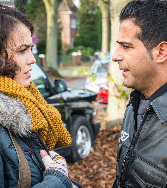 "Notruf Hafenkante - Paulines Fall": Auf einem Gehweg am Straßenrand stehen sich der Polizist Tarik Coban (Serhat Cokgezen) und Pauline Becker (Lucie Heinze) gegenüber und sehen sich an. Im Hintergrund sind parkende Autos, Bäume und Häuser zu sehen.