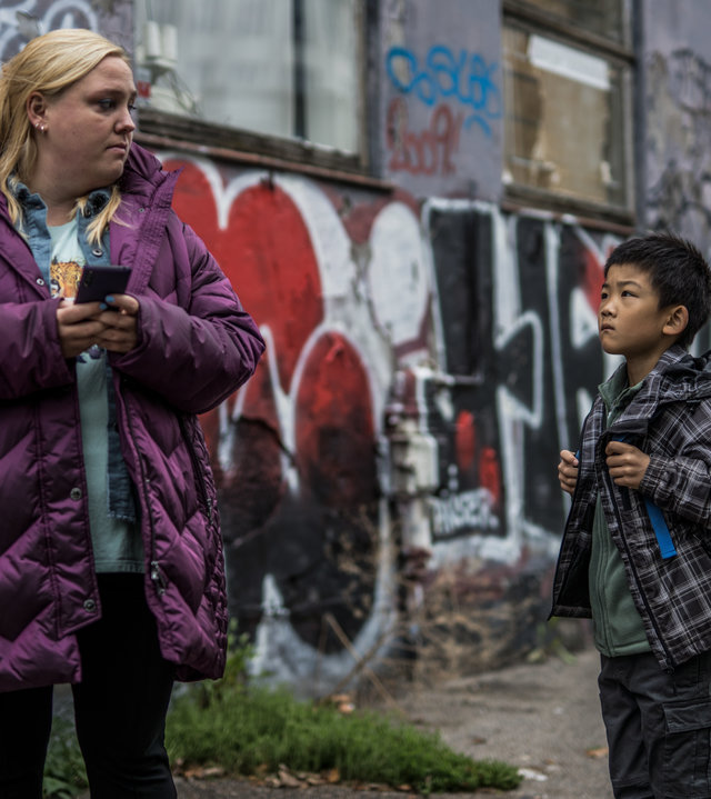 "Elvira - Sun": Elvira (Sara Klein) und der kleine Junge Sun (Oliver Ye Lu) stehen vor einer mit Graffiti beschmierten Hauswand.