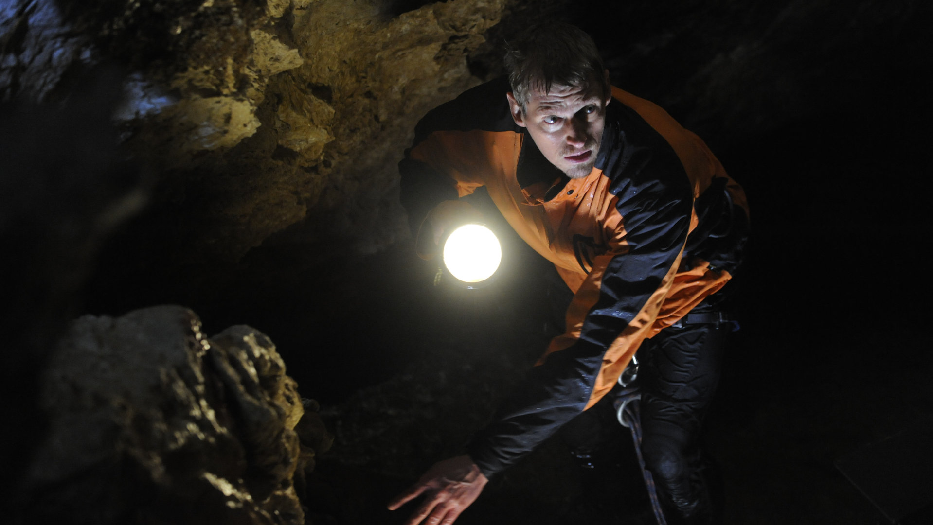 "Die Bergretter - Nur die Hoffnung zählt": Andreas Marthaler (Martin Gruber) sucht in einer Höhle. Er leuchtet mit der Taschenlampe den Weg aus.