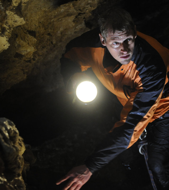 "Die Bergretter - Nur die Hoffnung zählt": Andreas Marthaler (Martin Gruber) sucht in einer Höhle. Er leuchtet mit der Taschenlampe den Weg aus.