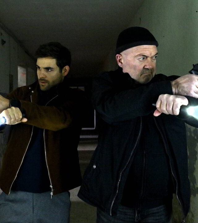 "Ein starkes Team - Das letzte Opfer": Nils Makowski (Lucas Reiber) und Otto Garber (Florian Martens) stehen in einem breiten dunklen Gang. Das Gebäude ist heruntergekommen. Beide haben ihre Waffe gezogen und leuchten mit Taschenlampen in die entgegengesetzte Richtung.