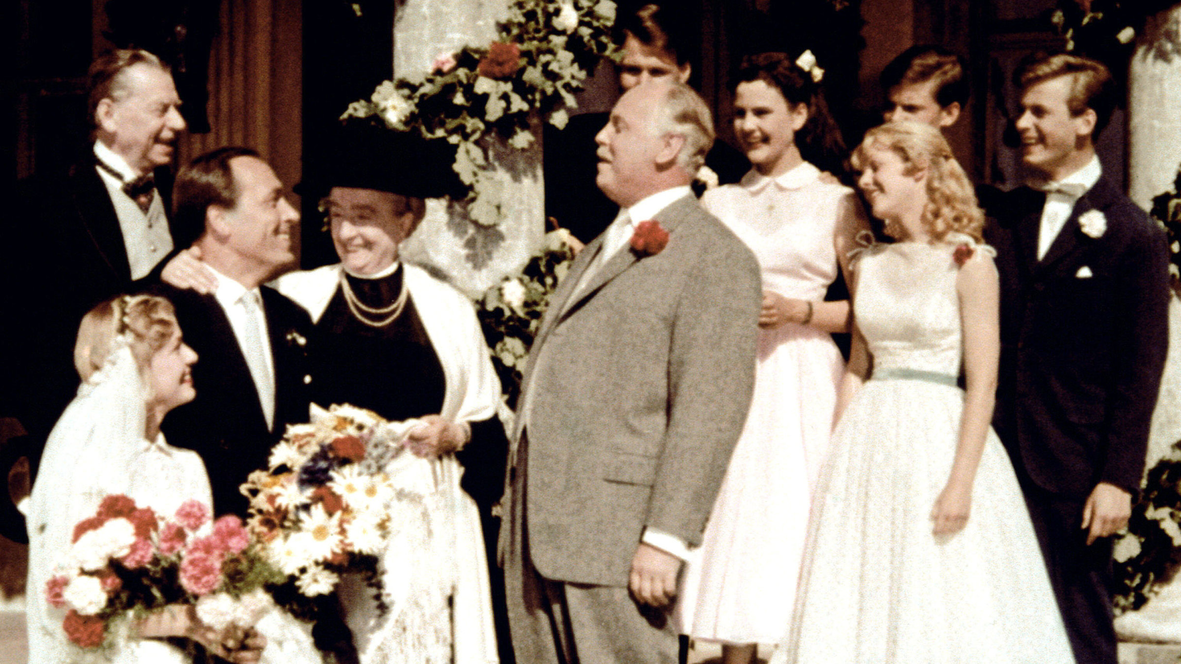 "Hochzeit auf Immenhof": Onkel Pankraz (Hans Nielsen, Mitte) gratuliert seiner Tochter Margot (Karin Andersen, li.) zu ihrer Hochzeit mit Jochen von Roth (Paul Kliner, 3. v. re.). Der reiche Winzer hat außerdem Oma Jatzens (Margarethe Haagen, 4. v. li.) Immenhof gerettet. Die Zukunft von deren Enkeln Dick (Angelika Meissner-Voelker) und Dalli (Heidi Brühl, re.) ist damit gerettet. Cousin Ethelbert (Matthias Fuchs, re.) hatte an dieser Rettung maßgeblichen Anteil.