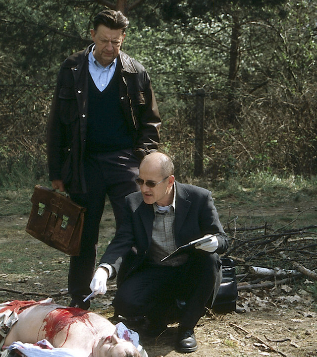 "Der letzte Zeuge - Die Frösche, die Kinder, der Tod": Dr. Robert Kolmaar (Ulrich Mühe) und Kommissar Joe Hoffer (Jörg Gudzuhn) knien in einem Wald neben der Leiche des Informatikers Heiner Wolf (Alexander Schönemann).