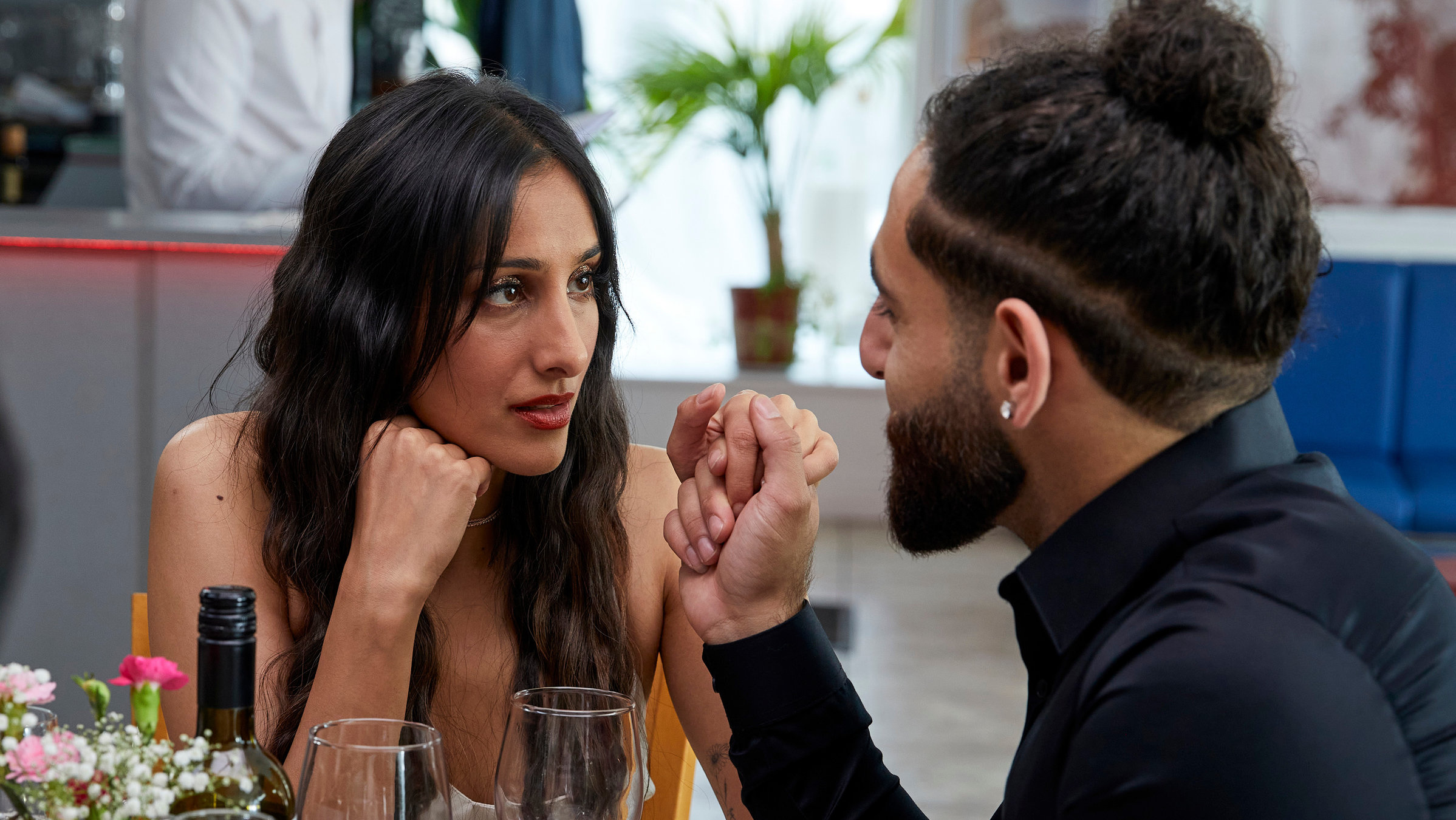 "Hullraisers - Durststrecke": Rana (Taj Atwal) und Adil (Merch Husey) sitzen nebeneinander und schauen sich innig an, während Adil Ranas Hand hält.