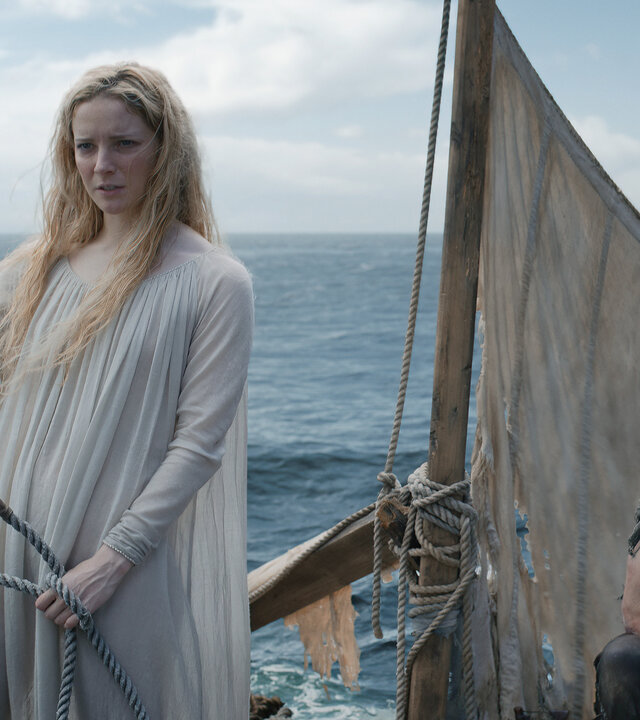 "Der Herr der Ringe: Die Ringe der Macht - Treibgut": Galadriel (Morfydd Clark) steht auf einem Floß mit einem kleinen Segel. Hinter ihr hockt Halbrand (Charlie Vickers). Im Hintergrund ist das Meer zu sehen.