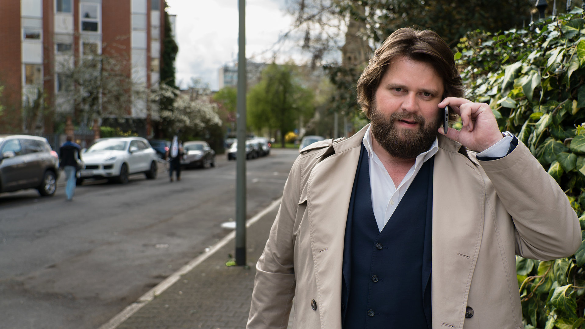 „Ein Fall für zwei – Familienbande“: Benni Hornberg (Antoine Monot, Jr.) steht auf dem Bürgersteig einer kaum befahrenen Straße und telefoniert.