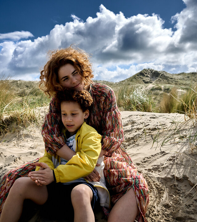 "Don't Fall, Dance - Wer oder was ich bin, ist nicht in diesem Körper": Emma (Hanna van Vliet) und Robin (Joshua Teijema) sitzen am Strand im Sand. Sie hat von hinten ihre Arme um ihn gelegt.