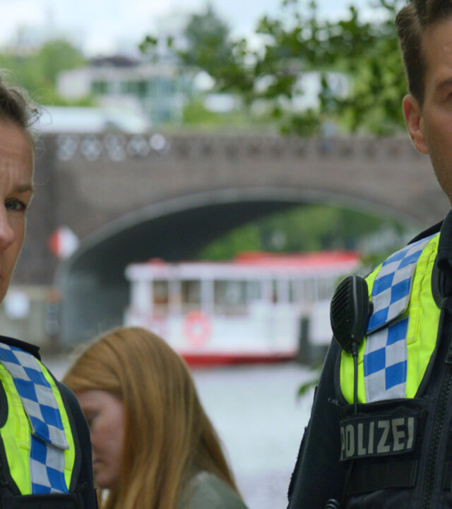 "Notruf Hafenkante - Verhext": Großaufnahme: Polizistin Franzi Jung (Rhea Harder-Vennewald) und ihr Kollegen Nick Brandt (Raúl Richter) stehen dicht nebeneinander im Freien und blicken beide in die gleiche Richtung.